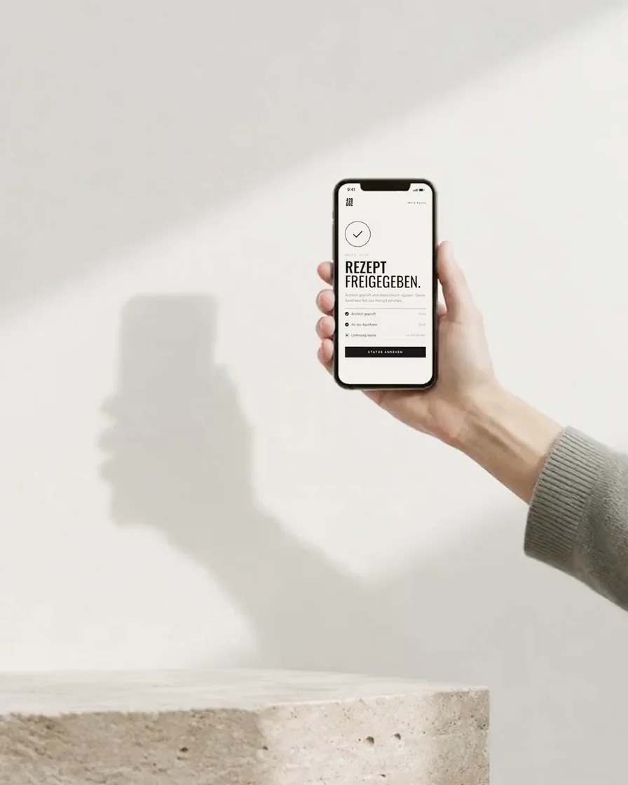 Hand hält ein Smartphone mit Bestätigung vor einer weißen Wand