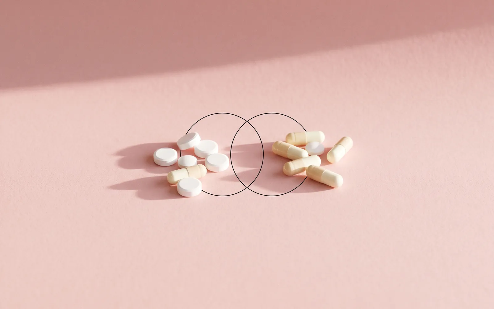 Stillleben: weiße Tabletten und Kapseln in zwei Gruppen, verbunden durch zwei verschlungene Kreise.